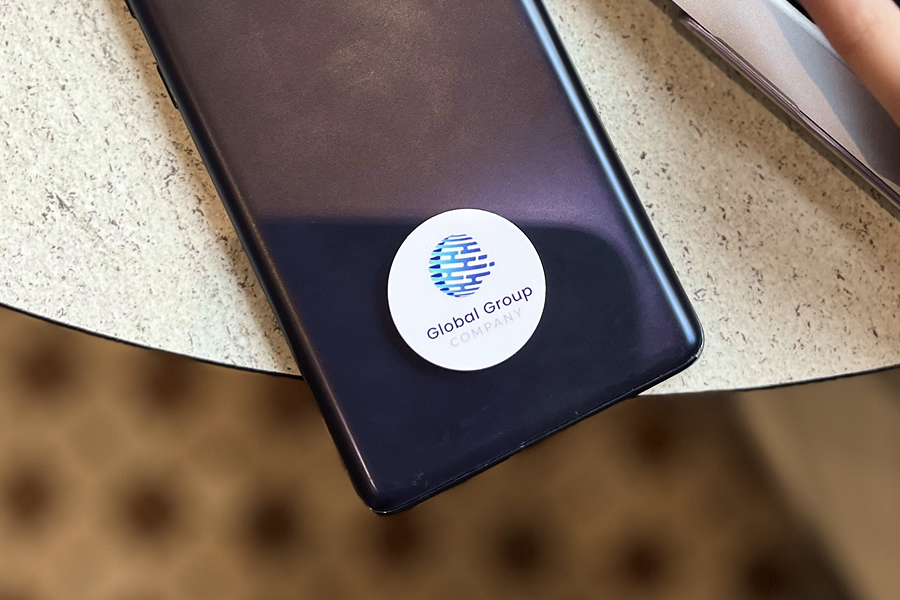 Custom branded One Good Card Mini NFC sticker featuring the Global Group logo on a smartphone
