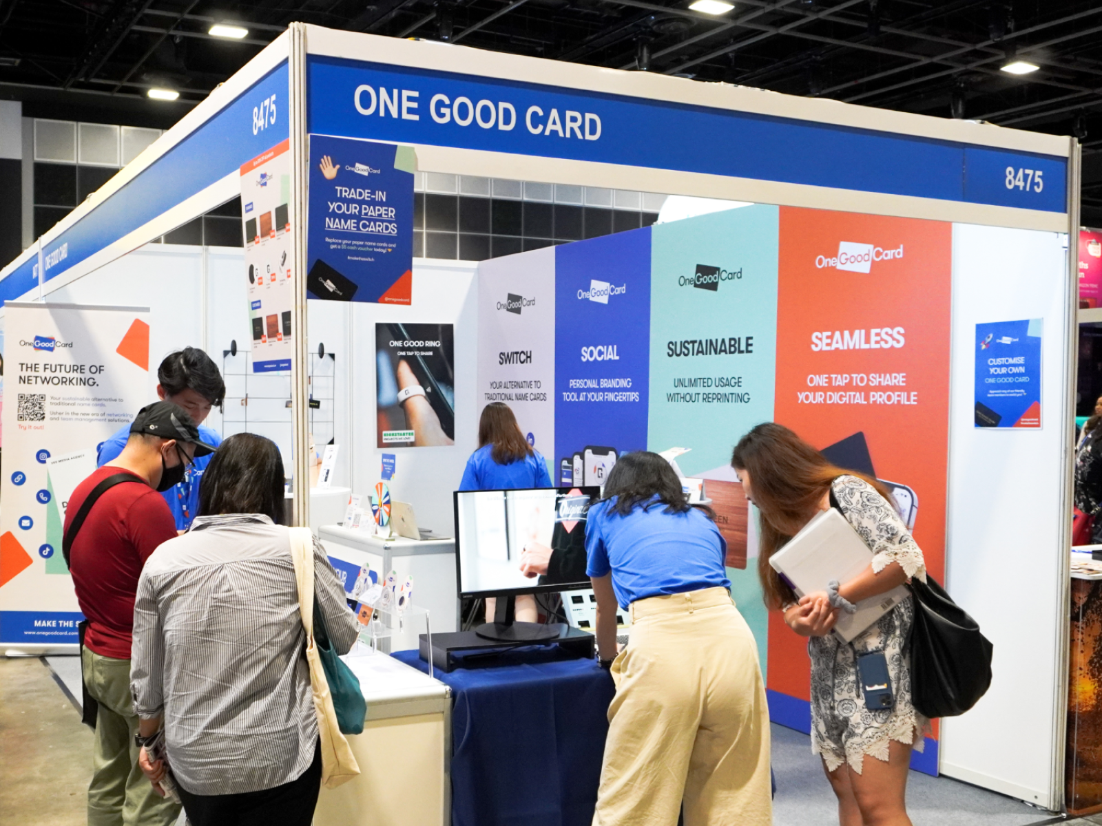 Visitors at the One Good Card exhibition booth, browsing card samples with the team