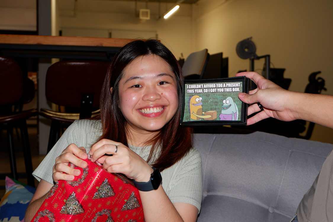 A team member laughing as she opens a gift at the office Christmas exchange