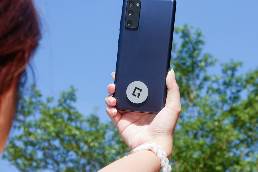 Smartphone fitted with a One Good Card Mini NFC sticker for sharing a digital business card anywhere