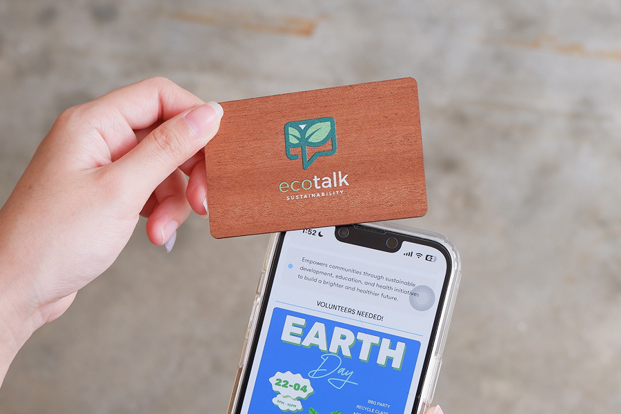 Custom branded wooden NFC business card with the ecotalk logo beside a smartphone